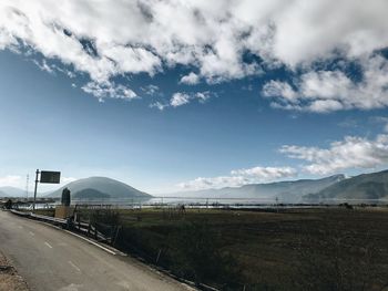 Road amidst field against sky