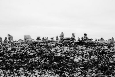 Stack of stones on field against clear sky