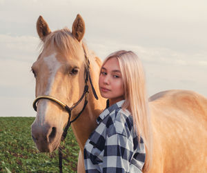 Young woman with horse against sky