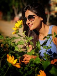 Smiling young woman wearing sunglasses by plants