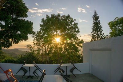 Empty chair by swimming pool against sky during sunset