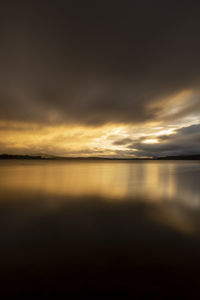 Scenic view of sea against dramatic sky during sunset