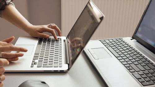 Cropped hands working over laptop at desk in office