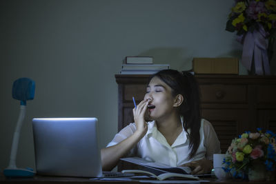 Young woman using phone while sitting on table