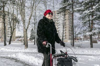 Woman standing by bare trees during winter