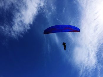 Low angle view of paragliding against blue sky