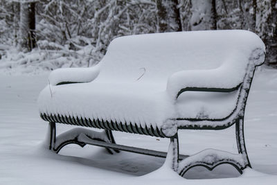 Close-up of empty bench on snow covered field