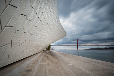 Bridge over river in city against cloudy sky