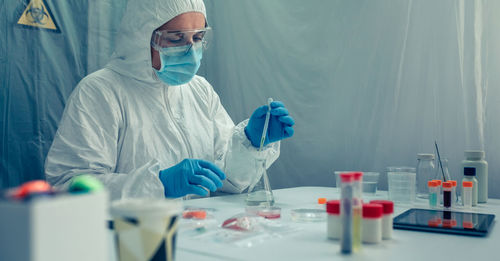 Scientist in protective suit working over chemical at laboratory