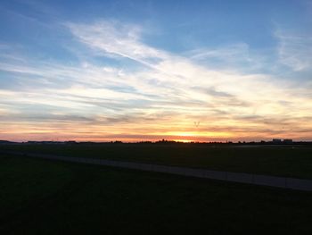 Scenic view of silhouette field against sky at sunset