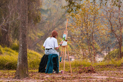 Young lady painting a forrest and creek scene in texas. 