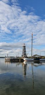 Sailboat on pier by lighthouse against sky