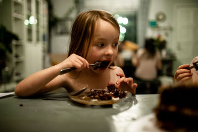 Young girl with surprised face while eating cake