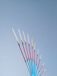 Low angle view of multi colored pencils against clear blue sky