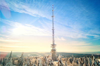 Communications tower in city against cloudy sky