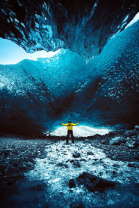 Rear view of man standing on snowcapped mountain during winter