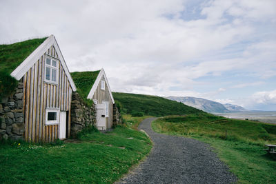 Road by cottages against sky