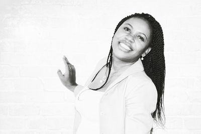 Portrait of smiling young woman against white wall