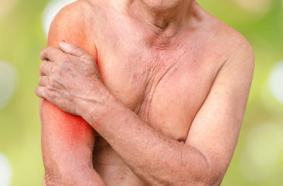 Digital composite image of shirtless man touching while suffering from shoulder pain against white background