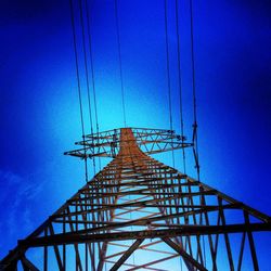 Low angle view of electricity pylon against blue sky