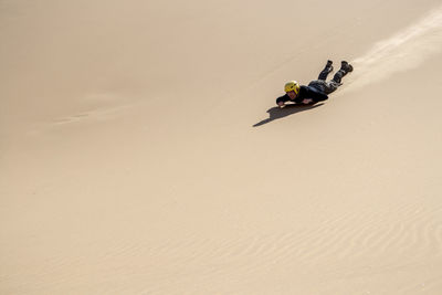 Man sliding down on a board, sandboarding, in the namibian dunes. copy space provided.