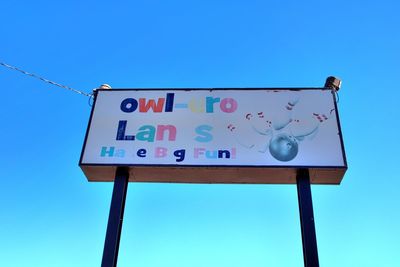 Low angle view of road sign against clear blue sky