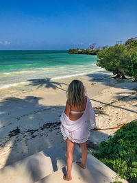 Rear view of woman on beach against sky