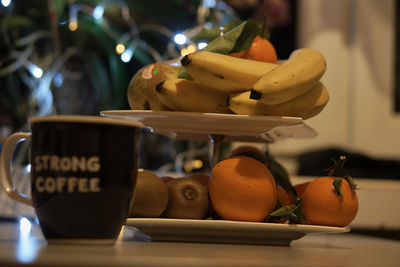 Fruits by coffee cup in plates on table