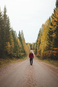 Man aged 23 wearing a checked  shirt walks along a foamy path surrounded by deciduous trees