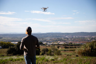 Rear view of man looking at airplane against sky