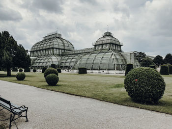 Garden by building against cloudy sky