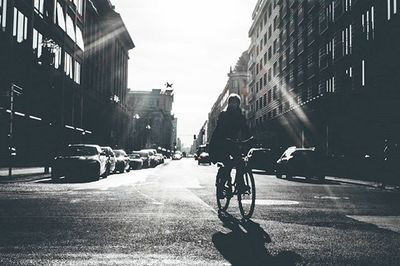 Rear view of man riding bicycle on city street