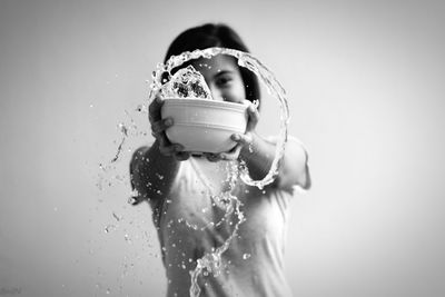 Young woman holding bowl with water against white background