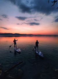 People on sea against sky during sunset