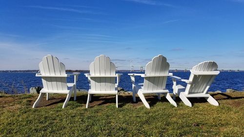 Chairs on beach against blue sky