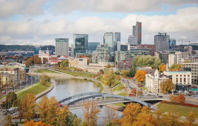 Bridge over river in city against cloudy sky