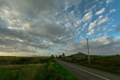 Road amidst field against sky