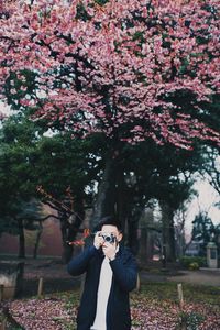 Young man with camera standing at park during winter