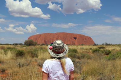 Rear view of woman wearing hat on field against sky