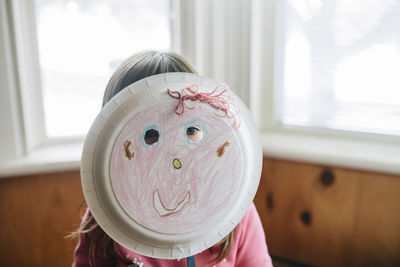 Playful girl looking away with plate mask