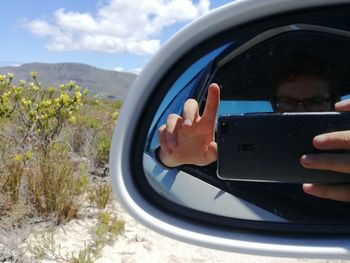 Reflection of man photographing car on side-view mirror