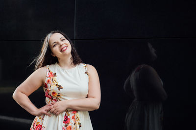 Portrait of happy confident plus size curvy young woman in front of black wall. smiling brunette