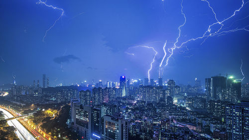 Lightning over illuminated buildings in city at night