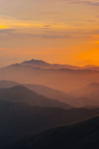 Scenic view of silhouette mountains against romantic sky at sunset