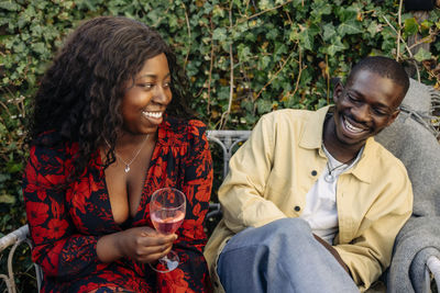 Smiling woman holding drink glass while enjoying with male friend at party