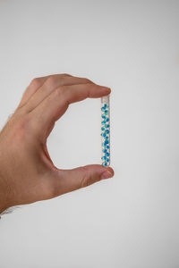 Close-up of hand holding ring over white background