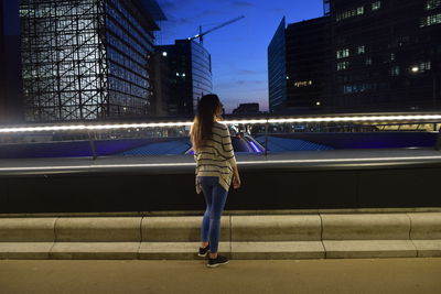 Rear view of woman walking on illuminated city at night