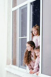 Happy girl looking through window at entrance
