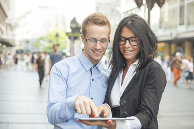 Portrait of a smiling young man using smart phone in city