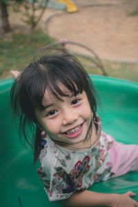 High angle portrait of cute smiling girl sliding in playground